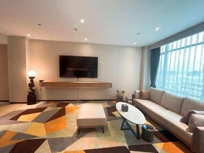 Uma sala de estar moderna com um sofá, uma mesa de centro e uma televisão de tela plana na parede.