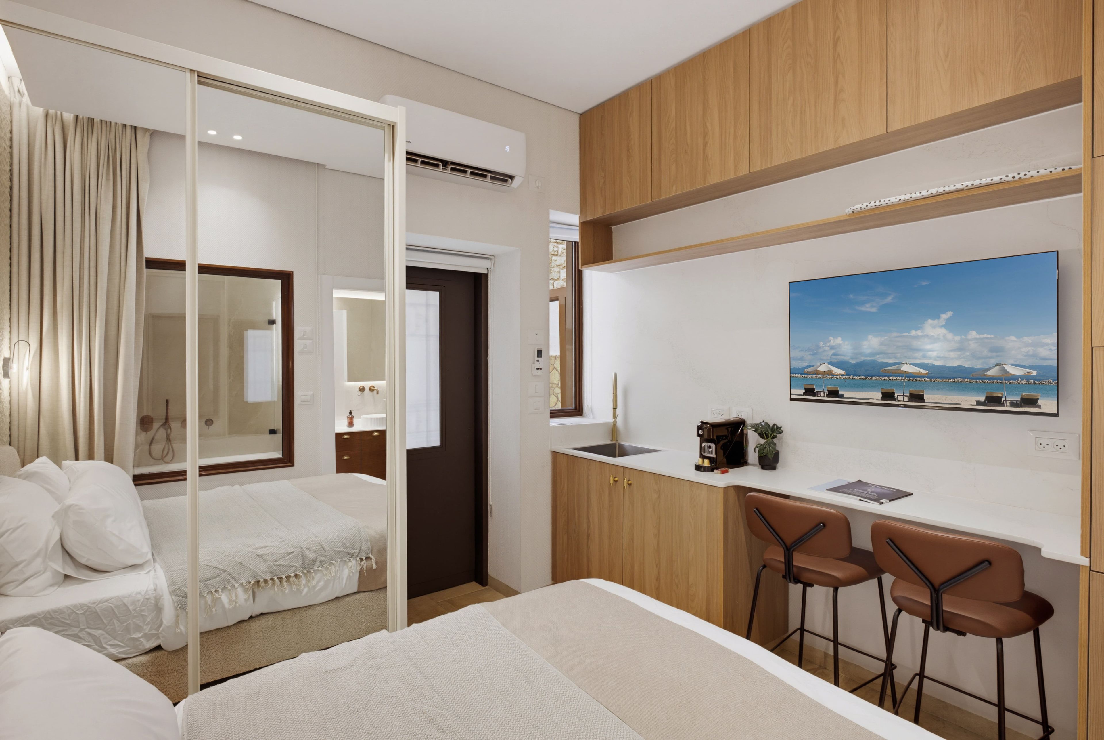 Habitación de hotel con una cama, un escritorio con dos sillas, un ventanal grande y un cuadro en la pared.