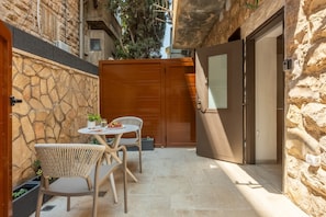 A narrow outdoor patio with stone walls, a wooden door, and a table with chairs. - Baraca Boutique- Apartments in Jerusalem (Jerusalem)
