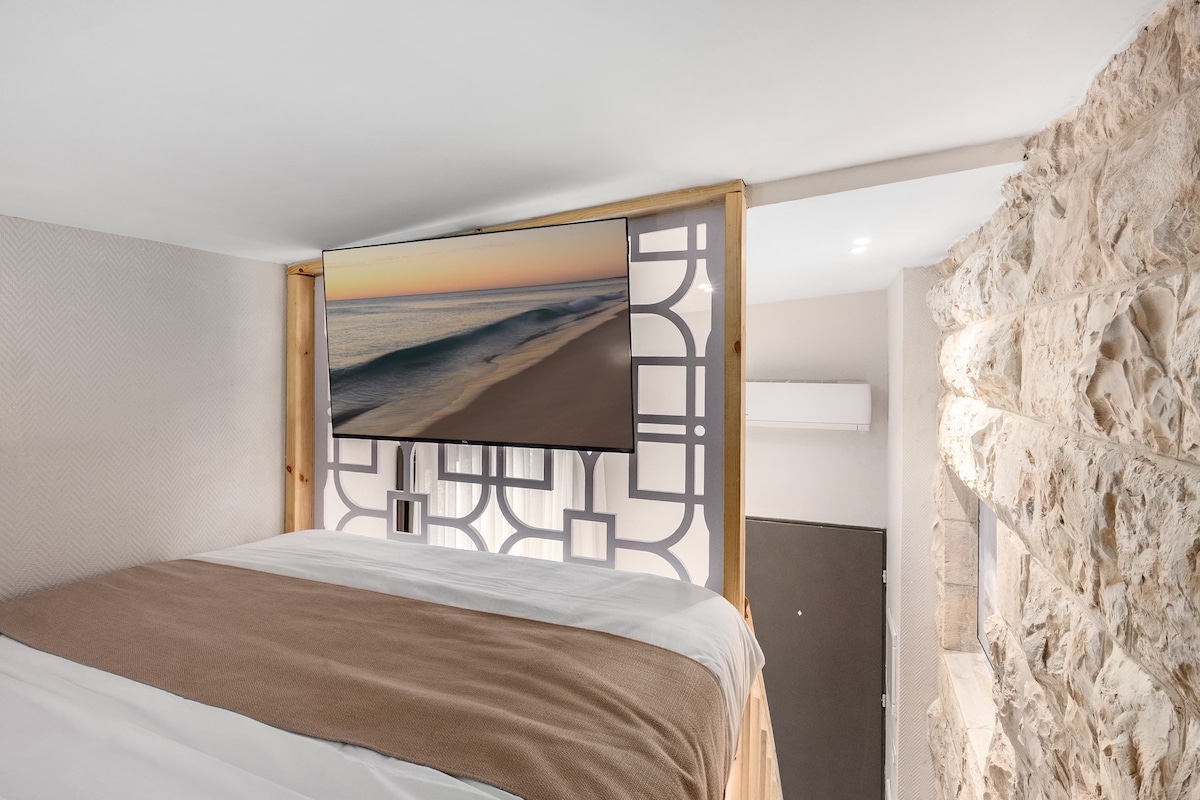 A bedroom with a bed, a decorative screen, and a stone wall.