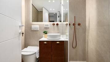 A modern bathroom with a white sink, wooden vanity, and a glass shower enclosure.