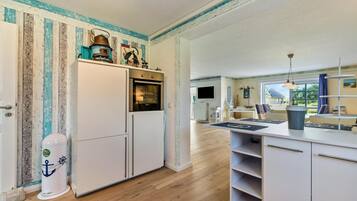 A compact kitchen with a built-in oven, a white refrigerator, and a wooden floor.