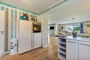 Una cocina compacta con horno integrado, un refrigerador blanco y piso de madera.