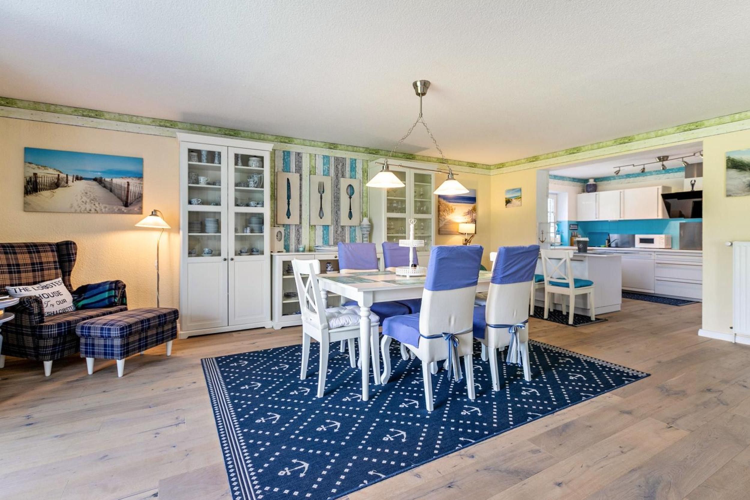 Un coin repas avec une table dressée pour quatre personnes, entourée de chaises dotées de coussins bleus.