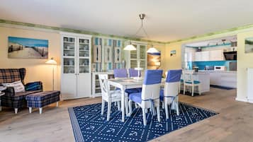 Un coin repas avec une table dressée pour quatre personnes, entourée de chaises dotées de coussins bleus.