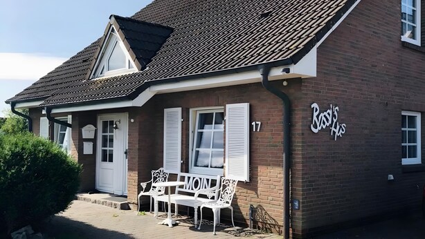 A two-story brick building with a tiled roof, a sign reading 'Boys' House,' and a paved driveway with a bench and chairs. - "Ebbe" Holiday Apartment with Private Terrace, Shared Garden, and Wi-Fi (Rodenäs)