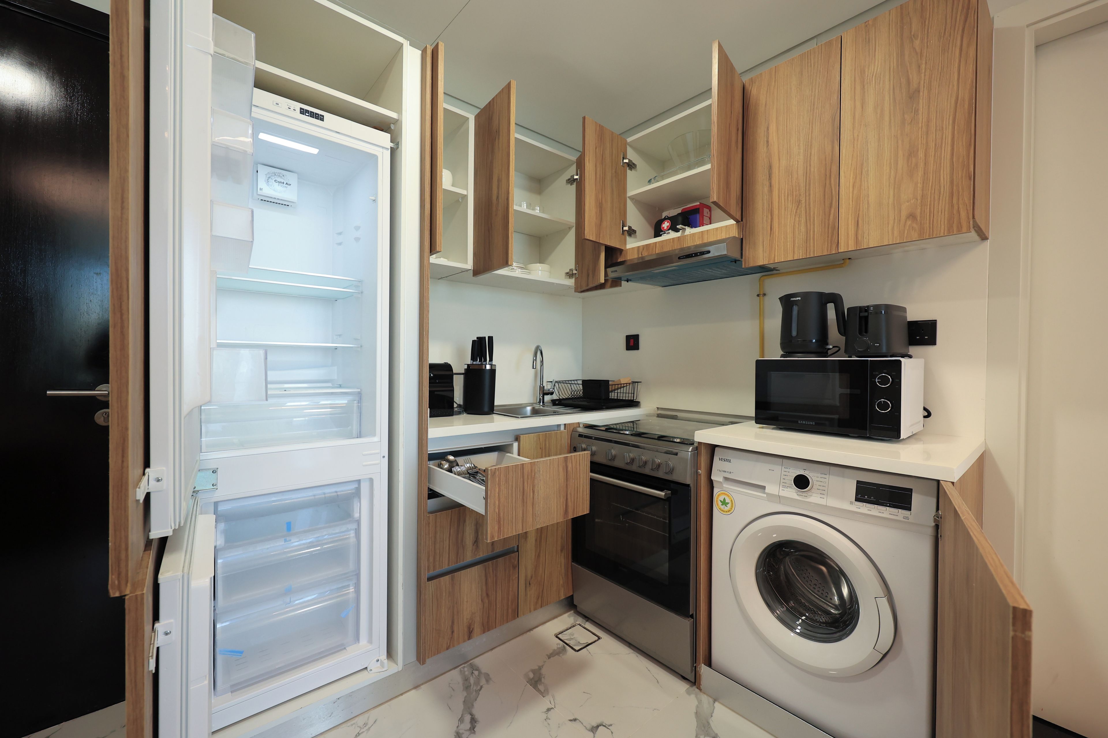 A compact kitchen with a built-in dishwasher, a microwave, a stove, and a washing machine.