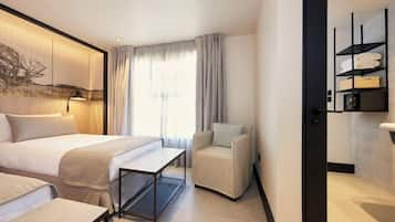 Habitación de hotel con una cama, una silla, un escritorio y una repisa en la pared con toallas.