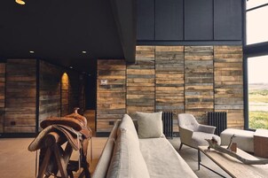 A modern interior with a sofa, armchair, and a rustic wooden wall.