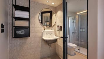 Un baño moderno con lavamanos integrado, un espejo redondo y cabina de ducha con vidrio.