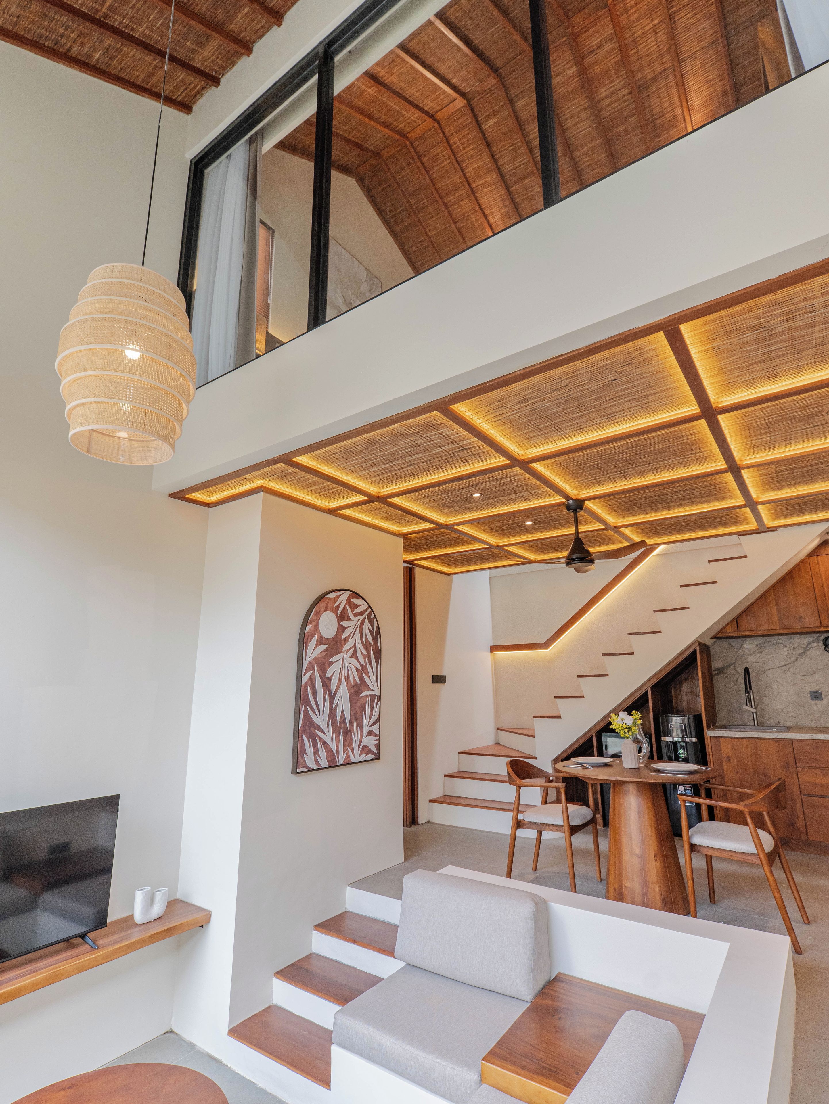 A modern interior with a staircase leading to a loft, a dining area, and a kitchen.