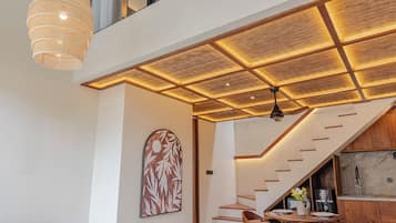 A modern interior with a staircase leading to a loft, a dining area, and a kitchen.