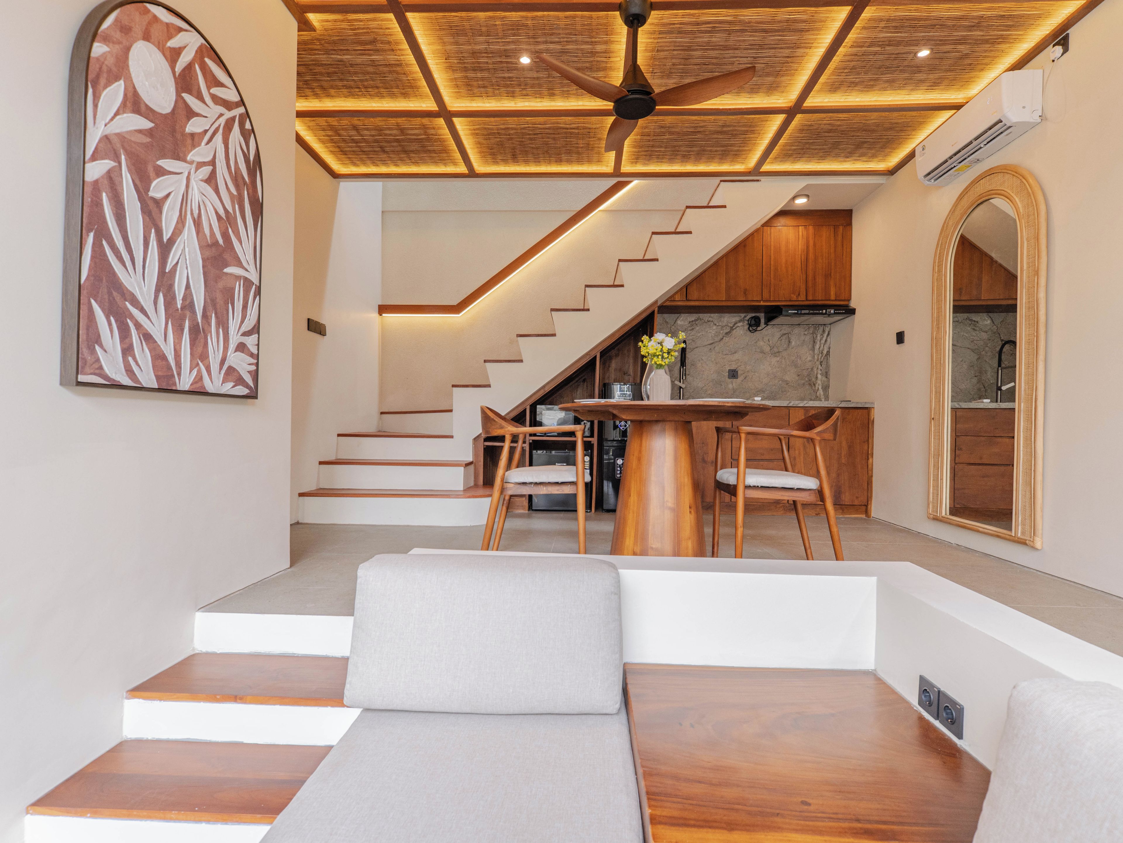 A modern interior with a staircase leading to a kitchen area, a dining table with chairs, and a seating area with a sofa.