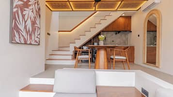 A modern interior with a staircase leading to a kitchen area, a dining table with chairs, and a seating area with a sofa.