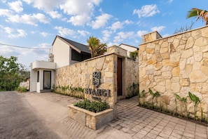A villa with a stone facade, a wooden door, and a paved entrance. - NEW 1BR Villa Svargi 1 Surf and Sanctuary Private pool (Pecatu, South Kuta, Badung Regency, Bali 80361)