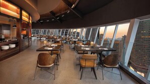 A modern restaurant with high ceilings, large windows, and a city view. - Yudu Hotel (Chongqing)