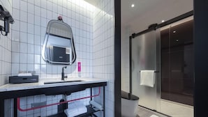 A modern bathroom with a large mirror, a sink, and a glass shower enclosure. - Yudu Hotel (Chongqing)