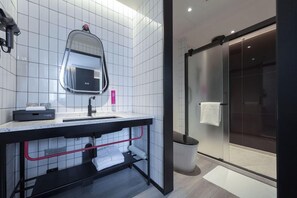 Une salle de bain moderne avec un grand miroir, un lavabo et une douche à l’italienne.
