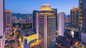 A high-rise building with a distinctive circular top, surrounded by other tall buildings in a cityscape. - Yudu Hotel (Chongqing)