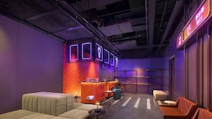 A modern lounge area with seating, a reception desk, and neon signage. - Yudu Hotel (Chongqing)