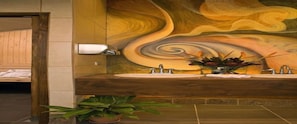Une salle de bain avec un meuble-lavabo en bois, deux vasques, un miroir et un tableau mural.