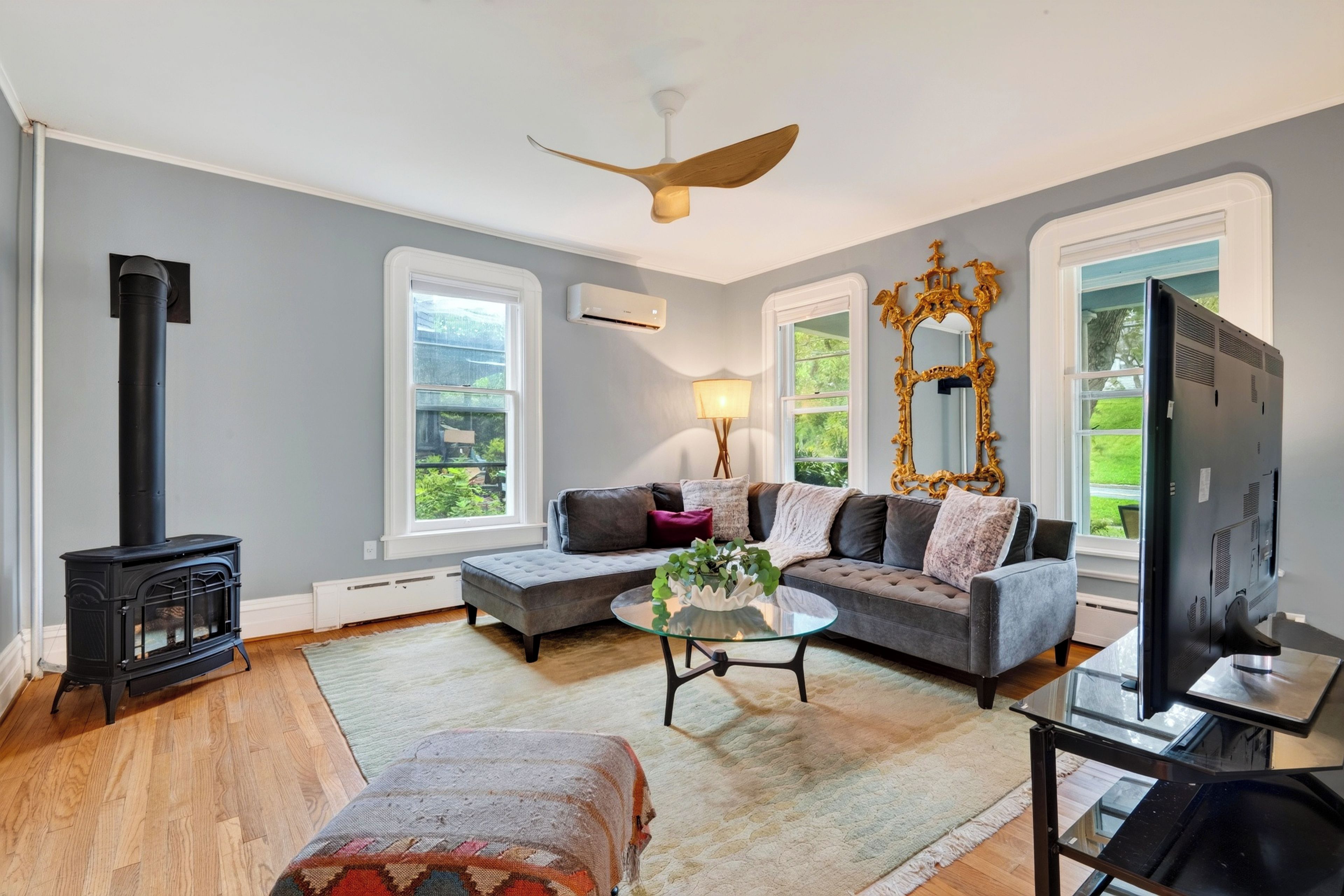 A living room with a fireplace, sofa, television, and a ceiling fan.