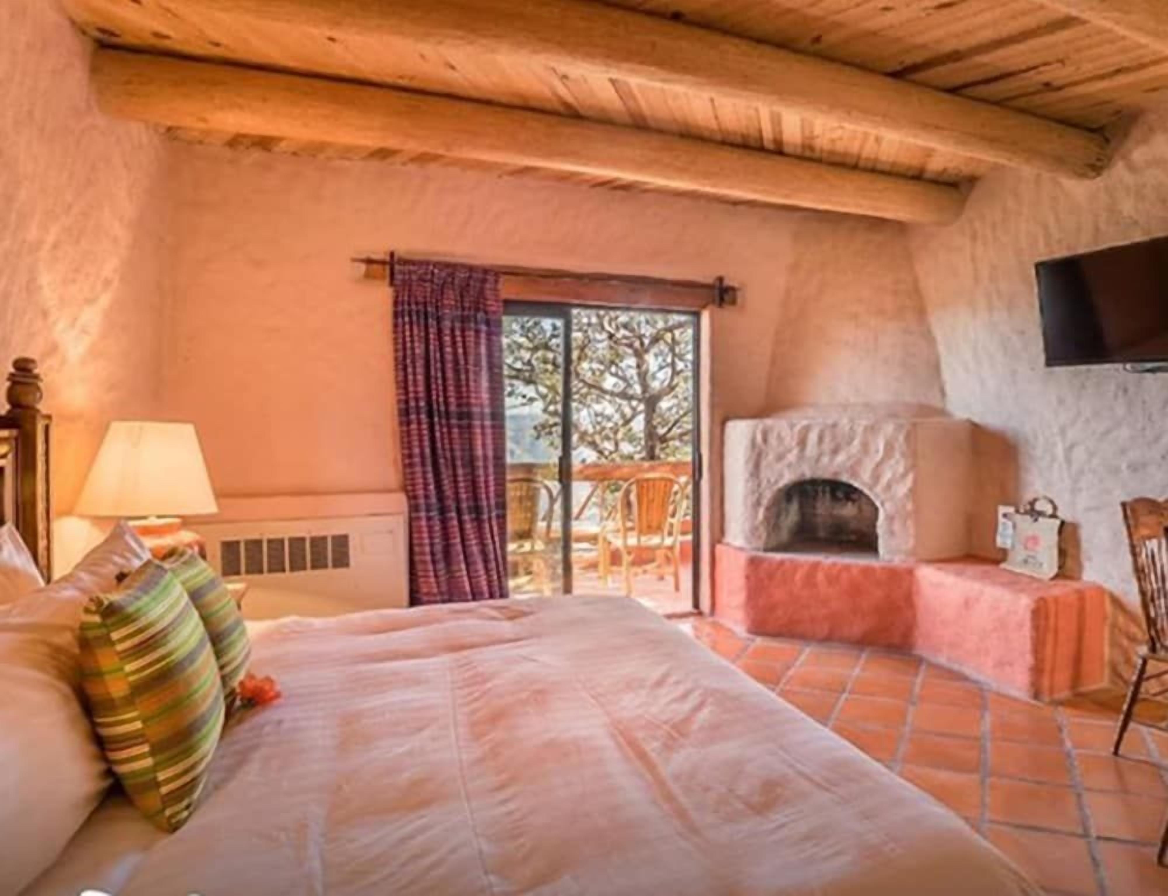 Un dormitorio con cama, chimenea, televisor y ventana con cortinas.