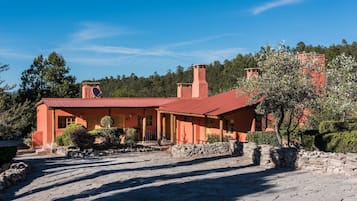 Una casa rústica con techo rojo, paredes de piedra y entrada pavimentada.