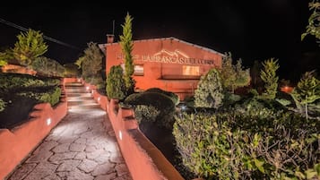 Una entrada de hotel con un camino de piedra que lleva al edificio, rodeada de vegetación cuidada.
