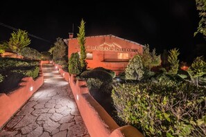 A hotel entrance with a stone pathway leading to the building, surrounded by well-maintained greenery.