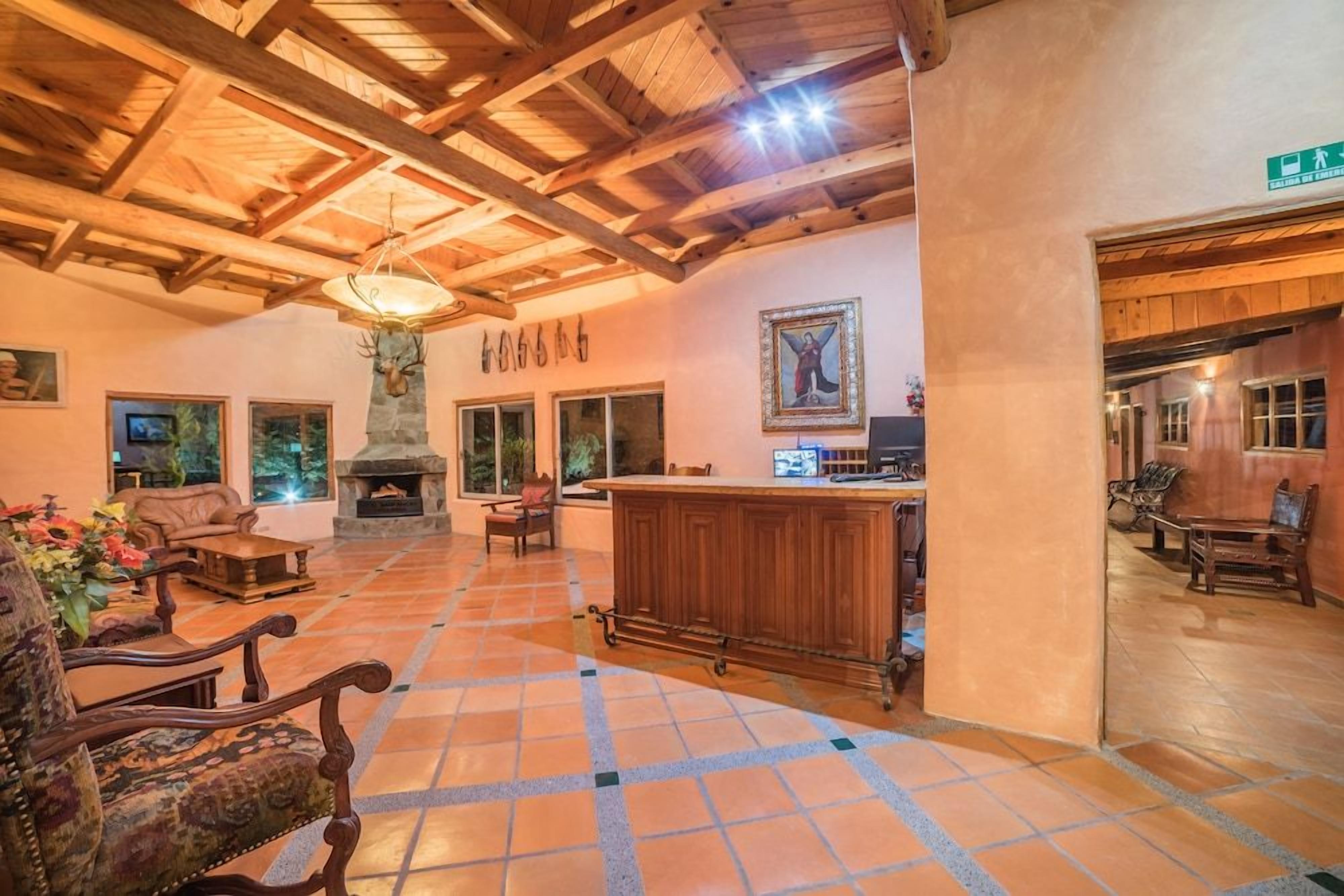 A spacious lobby with a fireplace, wooden furniture, and a stone column.