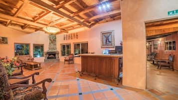Un hall espacioso con chimenea, mobiliario de madera y una columna de piedra.