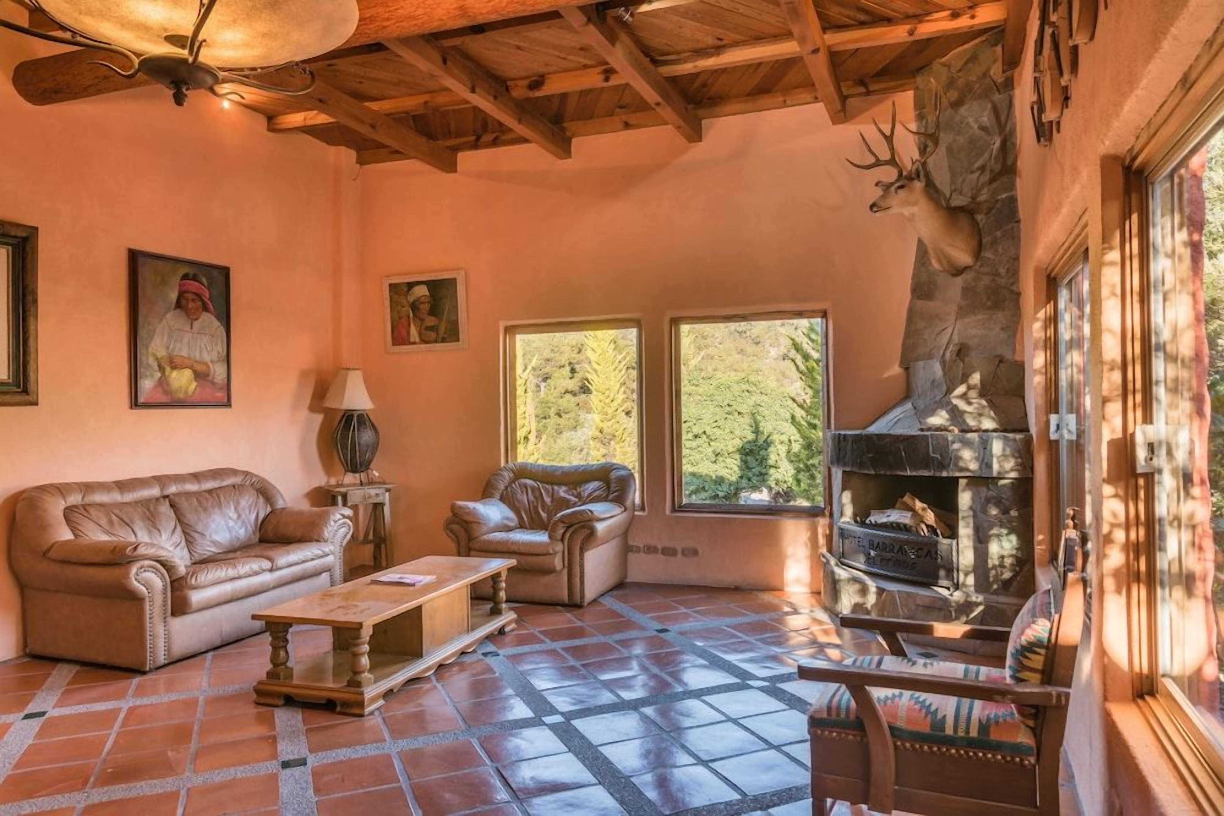 A cozy living room with a fireplace, leather sofas, and a stone wall.