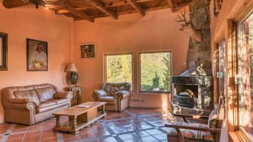 Una sala de estar acogedora con chimenea, sofás de cuero y una pared de piedra.