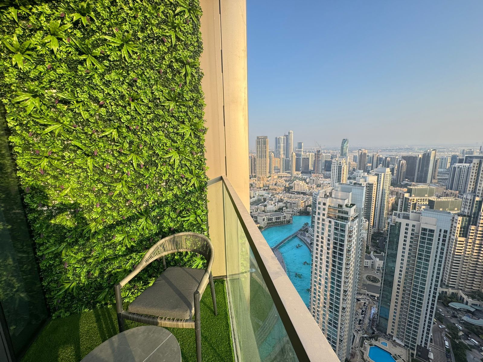 A balcony with a view of a cityscape, a chair, and a table.
