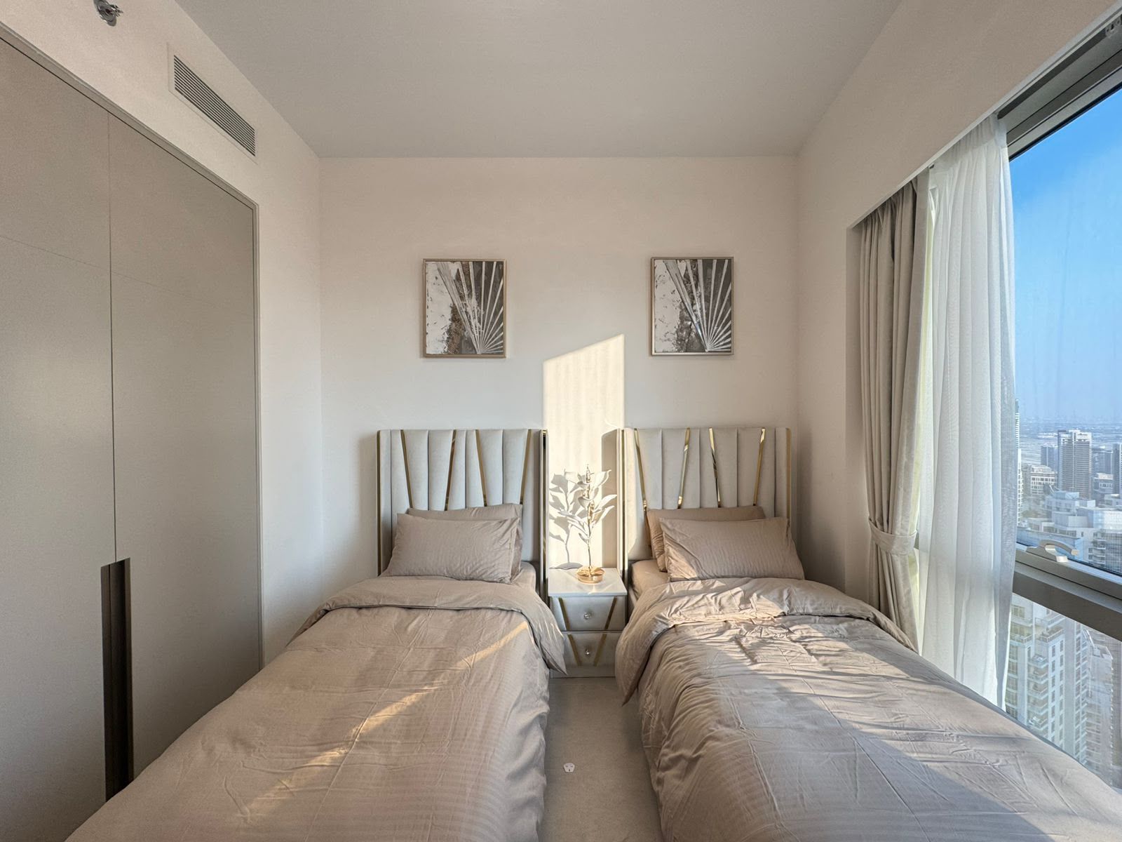 Une chambre d’hôtel avec deux lits, une vue sur la ville et des œuvres d’art aux murs.