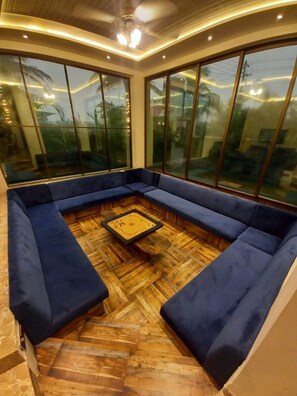 A room with a large sectional sofa, a wooden coffee table, and large windows.