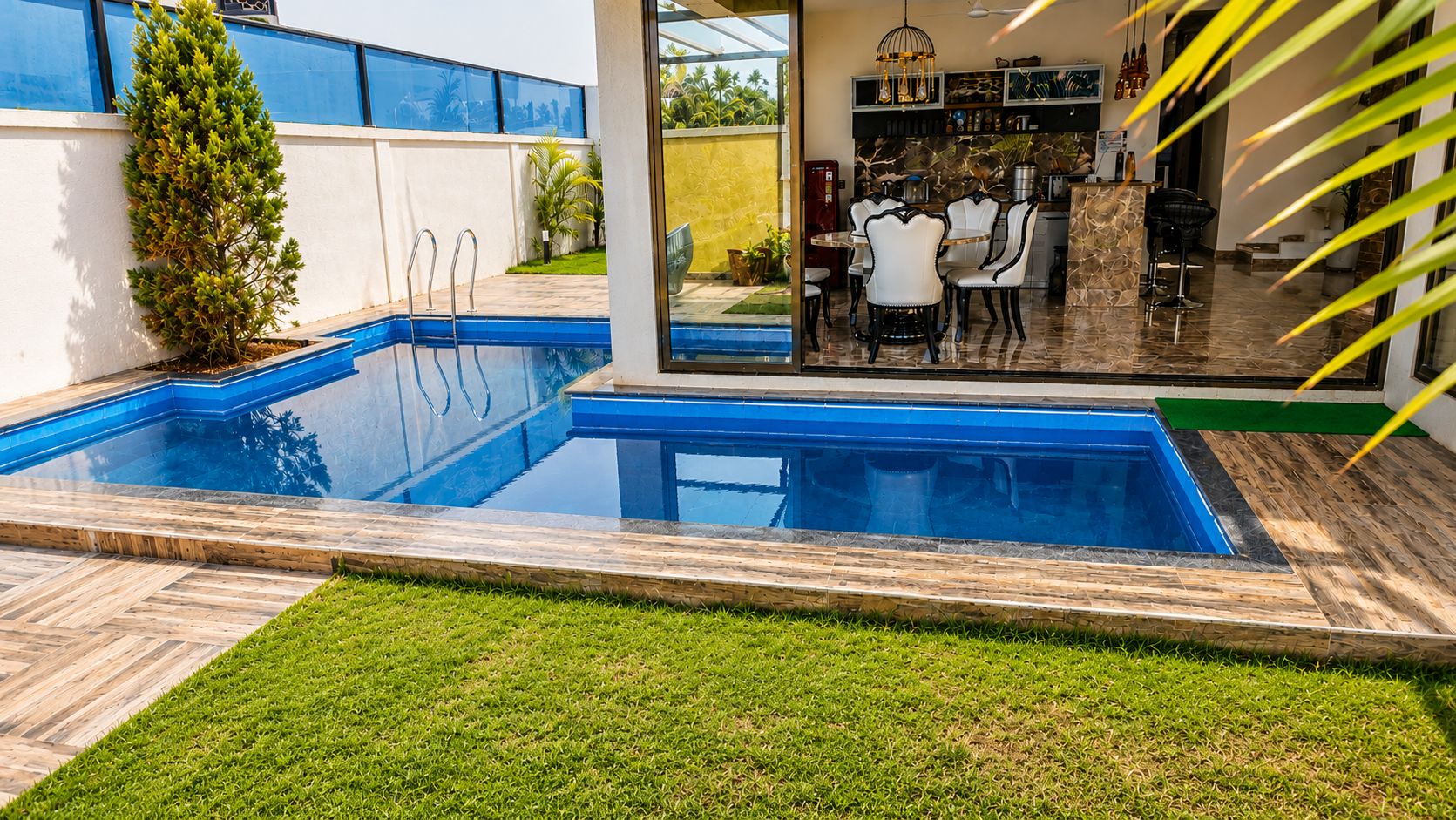 A swimming pool with a patio area, a bar, and a seating area with chairs.