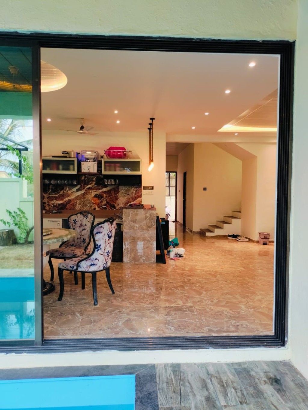 Un interior moderno con suelo de mármol, una zona de estar con una silla estampada y una cocina con encimeras de mármol.