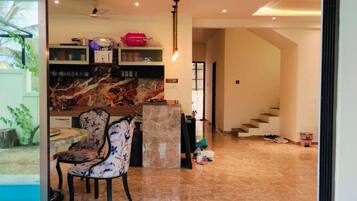 Un interior moderno con suelo de mármol, una zona de estar con una silla estampada y una cocina con encimeras de mármol.