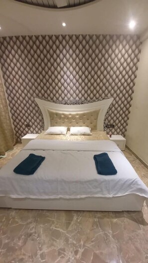 A bed with a tufted headboard, two bedside tables, and a patterned wall.