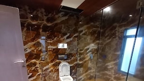 A modern bathroom with a marble wall, a toilet, and a glass shower enclosure. - 23 West, Malavli (Pune)