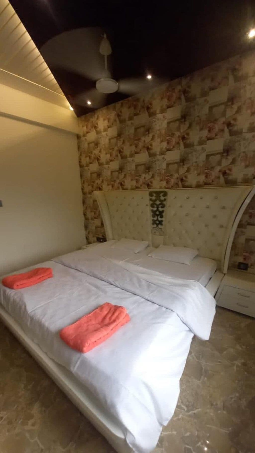 Un dormitorio con cama, cabecera y pared con diseño decorativo.