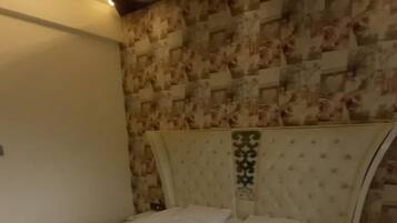Un dormitorio con cama, cabecera y pared con diseño decorativo.