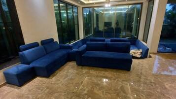 A modern living room with a sectional sofa, large windows, and a marble floor.