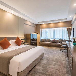 A modern hotel room with a large bed, a sofa, a desk, and a view of the outdoors. - West International Trade Hotel (Beijing)
