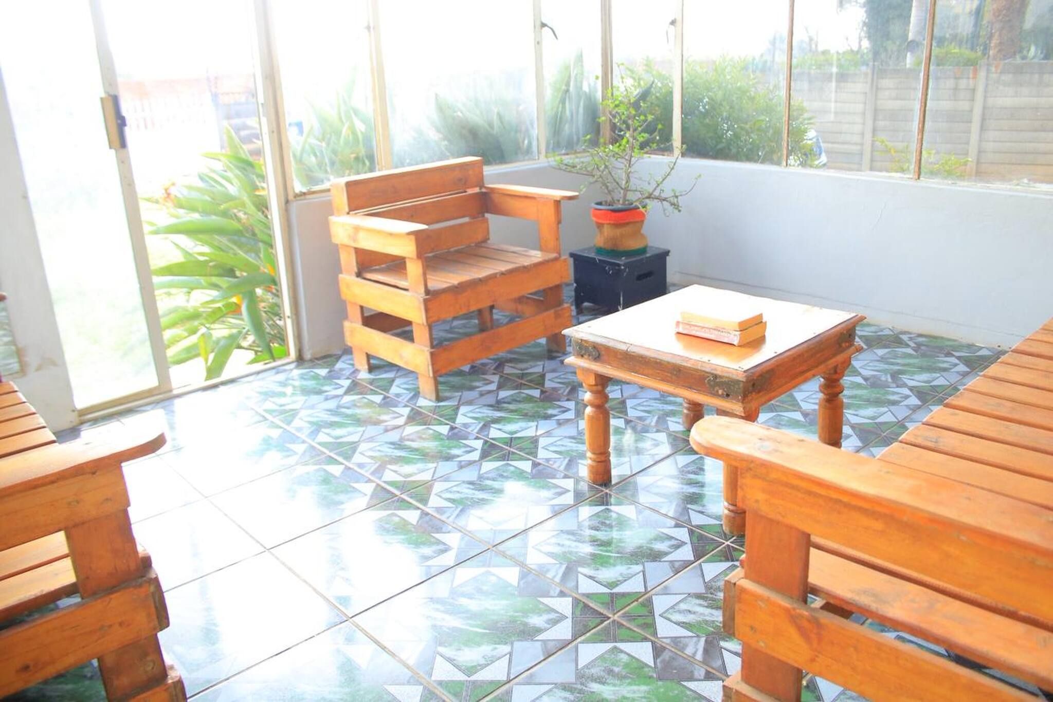 Un patio soleado con mobiliario de madera y suelo de baldosas.