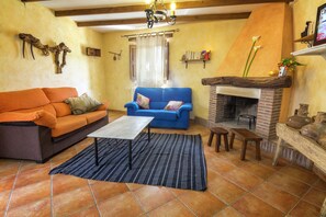 A living room with a fireplace, two sofas, a coffee table, and a patterned rug. - Charming Countryside Home in Laroya (Laroya)
