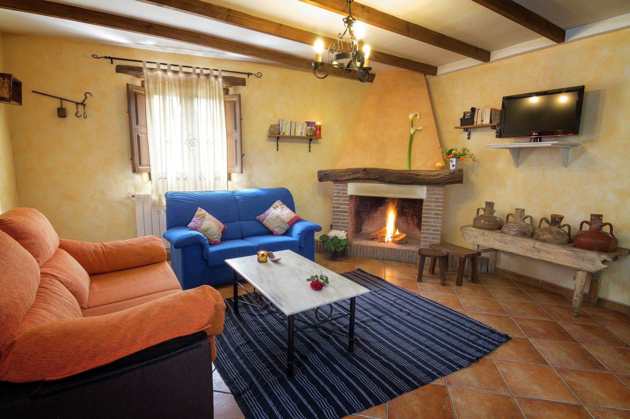 Uma sala de estar acolhedora com lareira, um sofá, uma mesa de centro e uma televisão na parede.