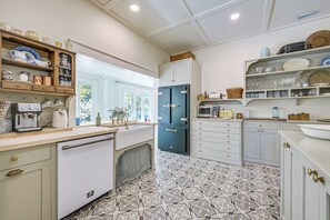 Cozinha com piso de azulejos estampados, armários brancos e diversos eletrodomésticos.